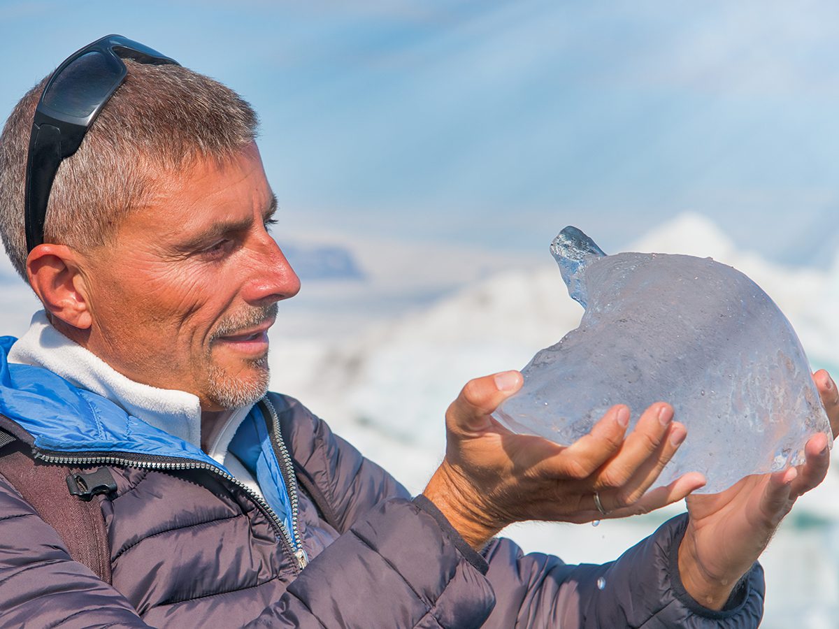 Scientist examining small iceberg in Jokulsarlon Glacier Lagoon
