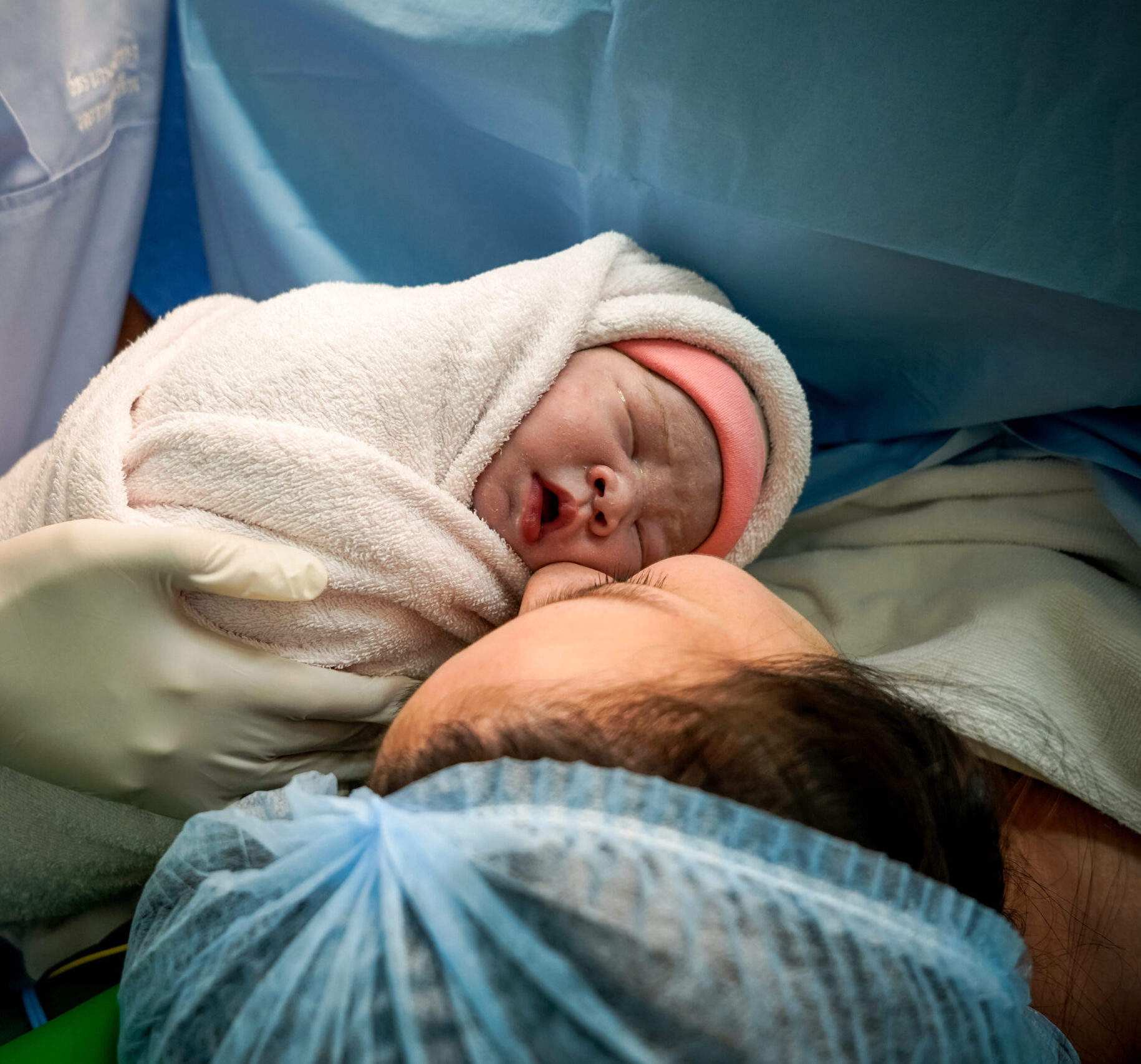 Mommy and baby newborn in the Cesarean section. First day of Little Baby Newborn Life in this world. First sight of mom and her newborn in operation room