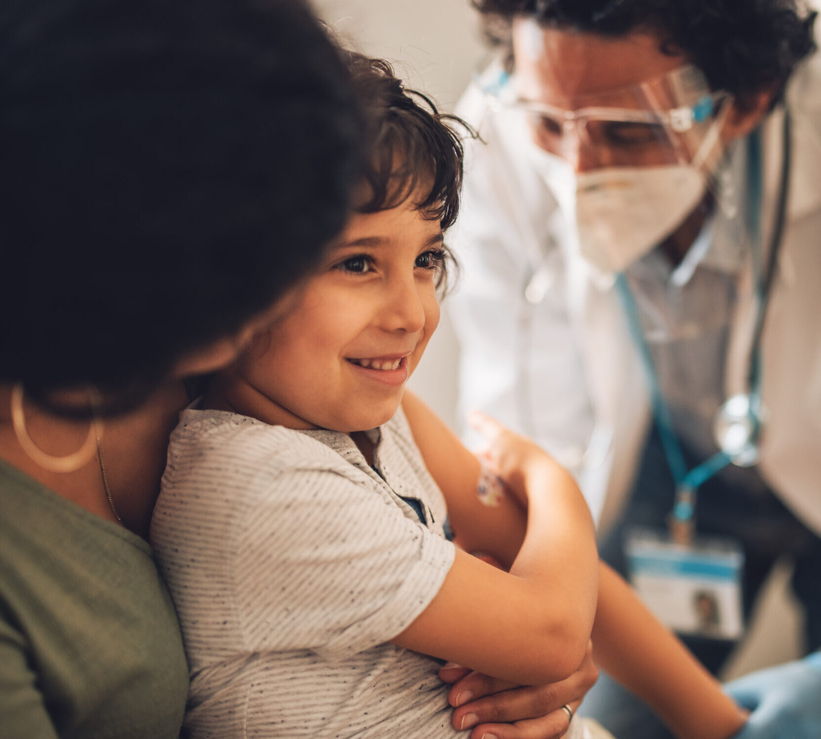 Happy boy with mom getting vaccine shot from a doctor