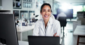 Computer, scientist and portrait of woman with smile for healthcare, medical research or innovation. Technology, laboratory and study with biologist in clinical trial for pharmaceutical development